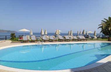 Girit, Yunanistan. Haziran 2019. Havuz kenarındaki şezlong, Hanya Körfezi Kuzey Girit 'te bir yüzme havuzuna bakmaktadır..