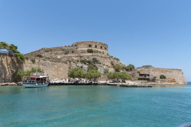 Spinalonga Adası, Girit, Yunanistan. Haziran 2019.Spinalonga'daki küçük doğal limanda küçük yolcu feribotu eski bir Cüzzam Kolonisi
