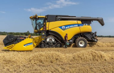 Cheltenham, Gloucestershire, England, UK, July 2019.  Combine harvester harvesting winter barley which after drying will go to brew beer. clipart
