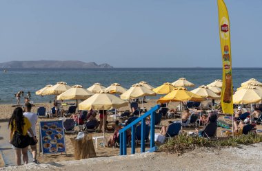 Iraklion, Girit, Yunanistan. Haziran 2019. Iraklion Havaalanı'na yakın acapulco plajı. Turistler güneşleniyor. Dia Adası Arka Planda ıssız.