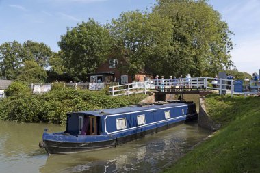 Devizes, Wiltshire, İngiltere, İngiltere. Ağustos 2019. Bir kafe binasının yanında Devies'teki Kennet & Avon Kanalı'nda bir kilitten çıkan mavi beyaz dar tekne.