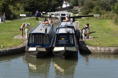 Devizes, Wiltshire, İngiltere, İngiltere. Ağustos 2019. İki dar tekne, Caen Hill'in kilitlerinin kilitlerinden birinin arasından birlikte geçiyor..