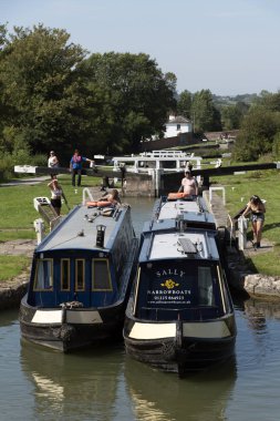 Devizes, Wiltshire, İngiltere, İngiltere. Ağustos 2019. İki dar tekne, Caen Hill'in kilitlerinin kilitlerinden birinin arasından birlikte geçiyor..