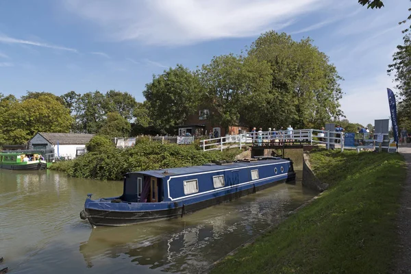Devizes, Wiltshire, İngiltere, İngiltere. Ağustos 2019. Bir kafe binasının yanında Devies'teki Kennet & Avon Kanalı'nda bir kilitten çıkan mavi beyaz dar tekne.