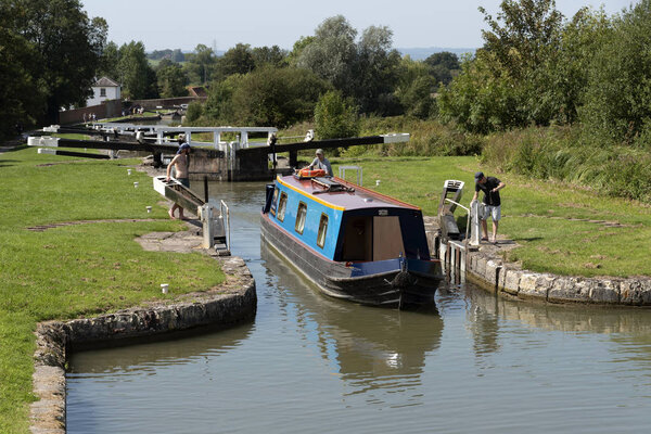 Devizes, Wiltshire, England, UK. August 2019. Narrowboat leaving a lock on the Caen Hill flight of locks on the Kennet and Avon Canal.