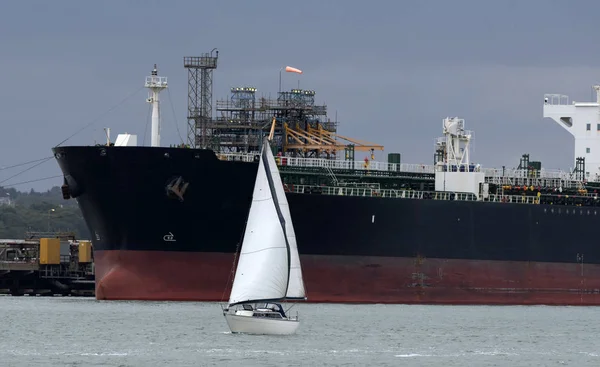 Southampton Water, İngiltere, İngiltere, Eylül 2019. Kimya, petrol ürünleri tankerleri bir rafineride kargo yükleme kapalı. Bu uçsuz bucaksız geminin yanından geçen bir yat.