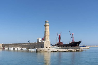 Rethymno Limanı, Batı Girit, Yunanistan. Eylül 2019. Venedik Habour 'daki deniz feneri ve Mv Catherina 1 yanında bir kargo gemisi..