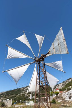 Lasithi Platosu, Doğu Girit, Yunanistan. Eylül 2019. Yel değirmeni sulama için bu manzaralı yerde su pompalıyor. Dağların Dikti aralığıyla çevrili..