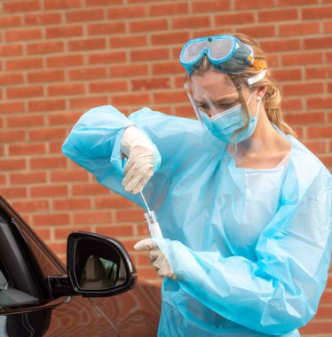 Salisbury, Wiltshire, İngiltere, İngiltere. Ağustos 2020. İngiltere 'de bir test istasyonunda çalışan koruyucu giysi, güneşlik, maske ve gözlük takan Covid-19 testçisi bir kadının portresi.