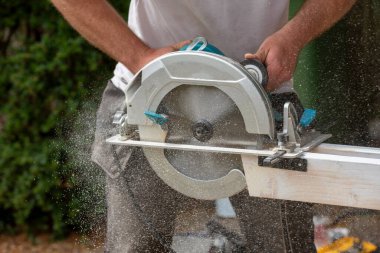 Hampshire, İngiltere, İngiltere. 2020 yılı. Marangoz, tahta kesmek için bir testere tutuyor. Tahta ince bir ahşap tozu oluşturuyor.. 