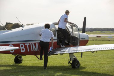 Gloucestershire, İngiltere, İngiltere. 2020 yılı. Bir öğrenci İngiliz havaalanından hocasıyla uçuş dersi almak üzere. Öğrenci pilot ve eğitmen uçağa biniyor..