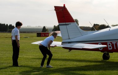 Gloucestershire, İngiltere, İngiltere. 2020 yılı. Bir öğrenci İngiliz havaalanından hocasıyla uçuş dersi almak üzere. Öğrenci pilot arka uçağı kontrol ediyor..