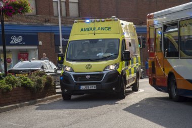 Margate, Kent, England UK. 2020.  An ambulance on a shout makes way through a car and local bus in busy traffic , clipart