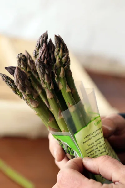 People gather asparagus in the field. Packing of asparagus on an industrial conveyor. A man is holding a green plant.