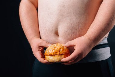 Karanlık bir arka plan üzerinde büyük bir göbek ile şişman adam. Diyet.