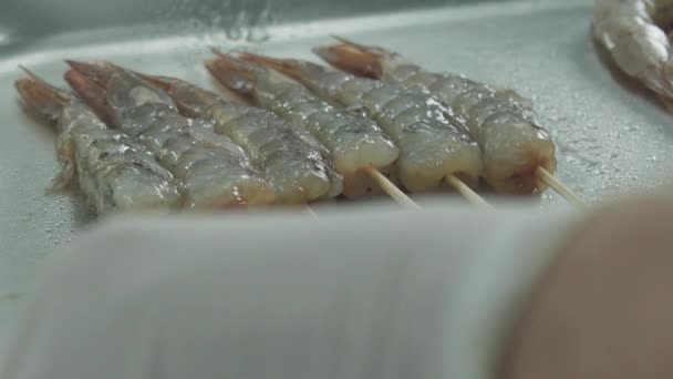 Рука опрокидывает креветки, застрявшие на палочках — стоковое видео