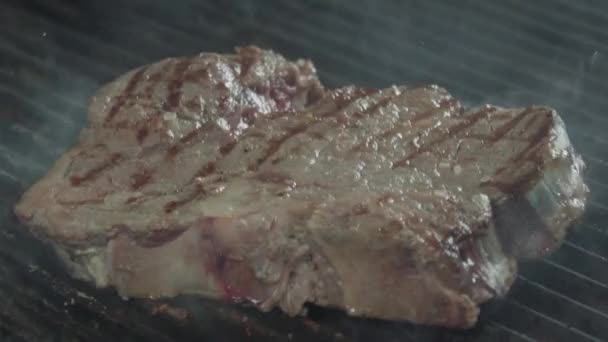 Trozo medio-raro de carne de res está cayendo sobre una superficie de freír — Vídeos de Stock