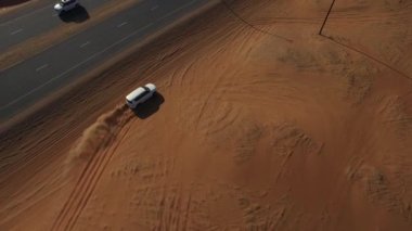 Kumlu yol boyunca beyaz Chrysler sürüklenir