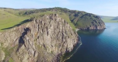 İnsansız hava aracı, Baykal Gölü yakınlarındaki kayalık uçurumdan dairesel bir uçuş yapıyor. Görüntü çerçevesi. Uçurumun tepesinde yapayalnız bir ağaç var.