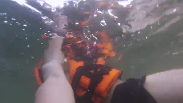 Парень в спасательной куртке плавает под водой — стоковое видео