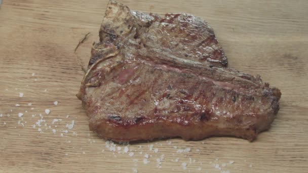 Gewürz wird auf das fertige saftige Steakstück gegossen. Gebratenes Fleisch in Flammen steht auf dem Brett — Stockvideo