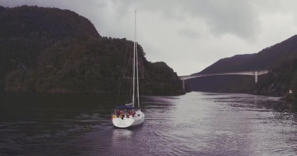 Lidé na jachtě plující podél fjordu mezi kopcovité pobřeží — Stock video