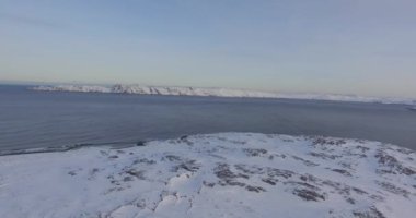 Dondurulmamış deniz koyu gri gökyüzü altında karla kaplı zemin