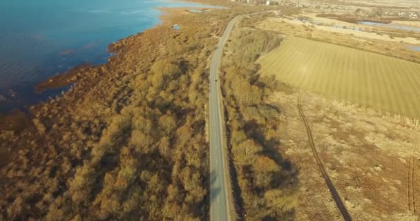 Luchtfoto van de snelweg door bossen velden water oppervlak in de herfst — Stockvideo