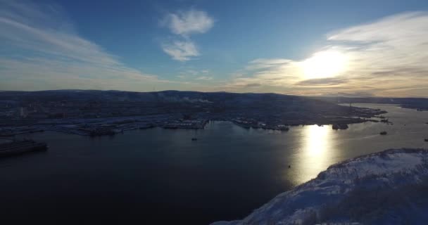 Snö landskap med staden på havet kusten upplyst av solnedgången ljus — Stockvideo