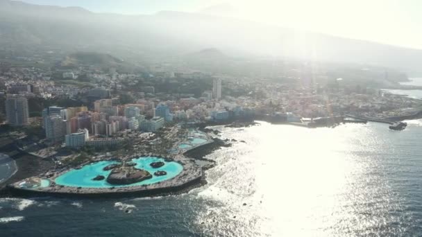 Береговая линия со зданиями и холмами на острове, омываемом океаном — стоковое видео