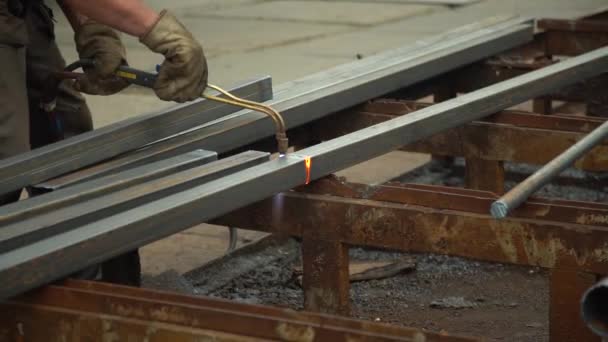 Arbetstagaren använder en svetsmaskin för att skära en metallstång i närbild — Stockvideo