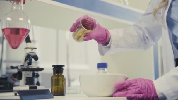 Ученый наливает золотой порошок в миску на стол крупным планом — стоковое видео