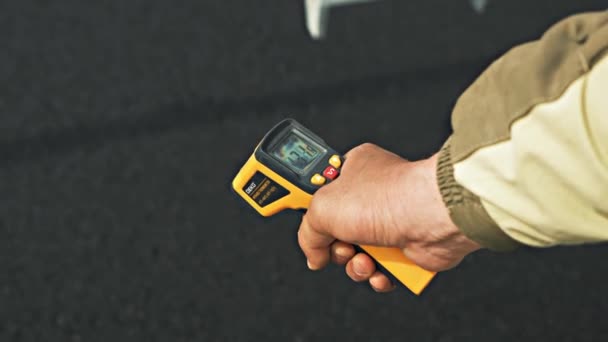 Работник дорожного сервиса вручную измеряет температуру асфальта — стоковое видео