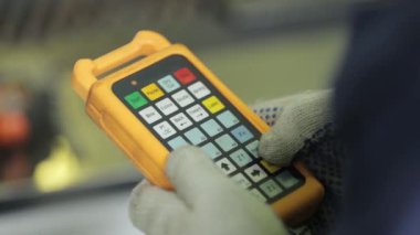 Makinenin uzaktan kumandasındaki düğmelere basarak kapatıyor