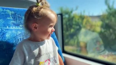 Küçük mutlu kız tramvaya binip pencereden dışarı bakıyor. Neşenin, çocukluğun ve şehir hayatının sembolü.