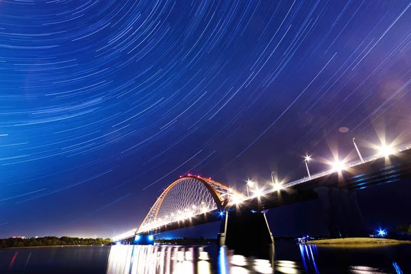 Nehir Ob gece boyunca köprü. Gece sky.in gökyüzü Köprüsü kızdırma ışıkların görünür yıldız izleri.