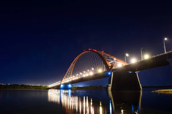 Bridge over the river Ob night. The lights of the bridge glow in the night sky.