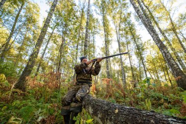 Avcı sarı yapraklar ağaçlarıyla çerçevede bir sonbahar ormandaki bir silahla