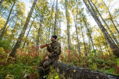 Avcı sarı yapraklar ağaçlarıyla çerçevede bir sonbahar ormandaki bir silahla