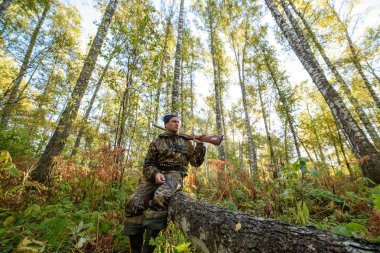 Avcı sarı yapraklar ağaçlarıyla çerçevede bir sonbahar ormandaki bir silahla