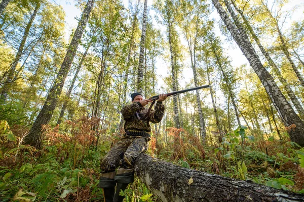 Avcı sarı yapraklar ağaçlarıyla çerçevede bir sonbahar ormandaki bir silahla