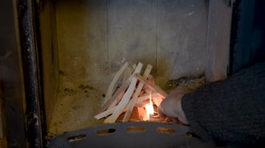 Bir adam şöminede ateş kindles. Yakacak odun kuru, soba tutuşmak.