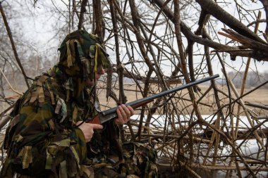 Dallardan kulübede bir avcı avını kollar.
