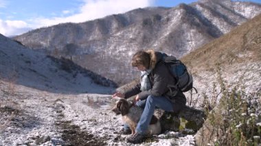 Köpeği olan kız dağlarda yürüyor. Kar yağıyor, güneş parlıyor..
