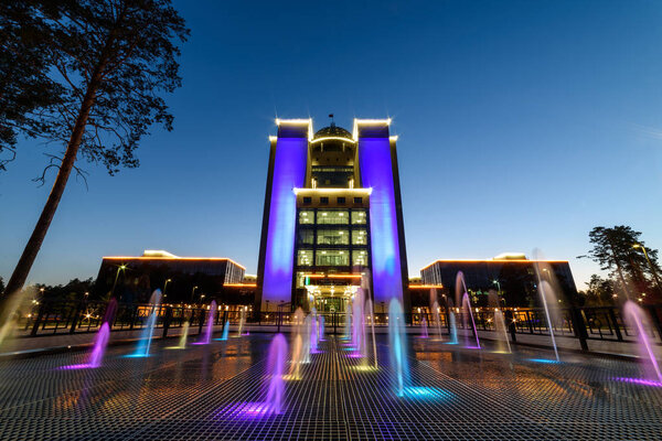 The building of the Novosibirsk University at night with illumination, a multi-colored fountain.