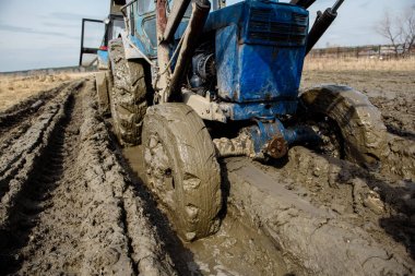 Tractor stuck in the mud on a bad road. Clay stuck on wheels. clipart