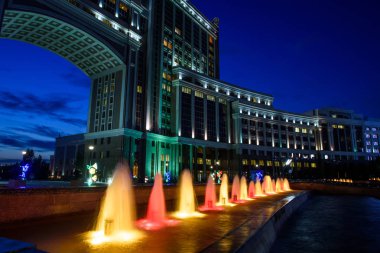 Nur-Sultan, Kazakistan, Ağustos 2019, Kazakistan'ın başkentinin merkezinde ki yüksek binaların arka planında aydınlatmalı çeşmeler.
