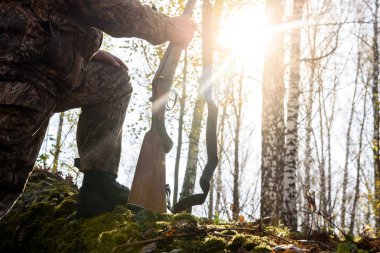 Avcı sonbaharda ormanda elinde silahla. Günaydın, güneşli hava..