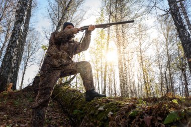 Avcı sonbaharda ormanda elinde silahla. Günaydın, güneşli hava..