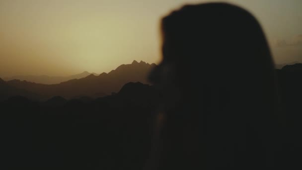 Silhouette di bella giovane donna camminare al tramonto nel deserto. Femmina che attraversa il deserto, dune, vento che soffia, 4k — Video Stock